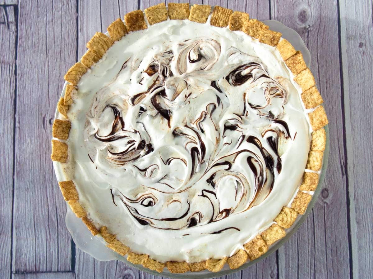 Ice cream pie with swirls of hot fudge on top and cinnamon cereal around the edges.