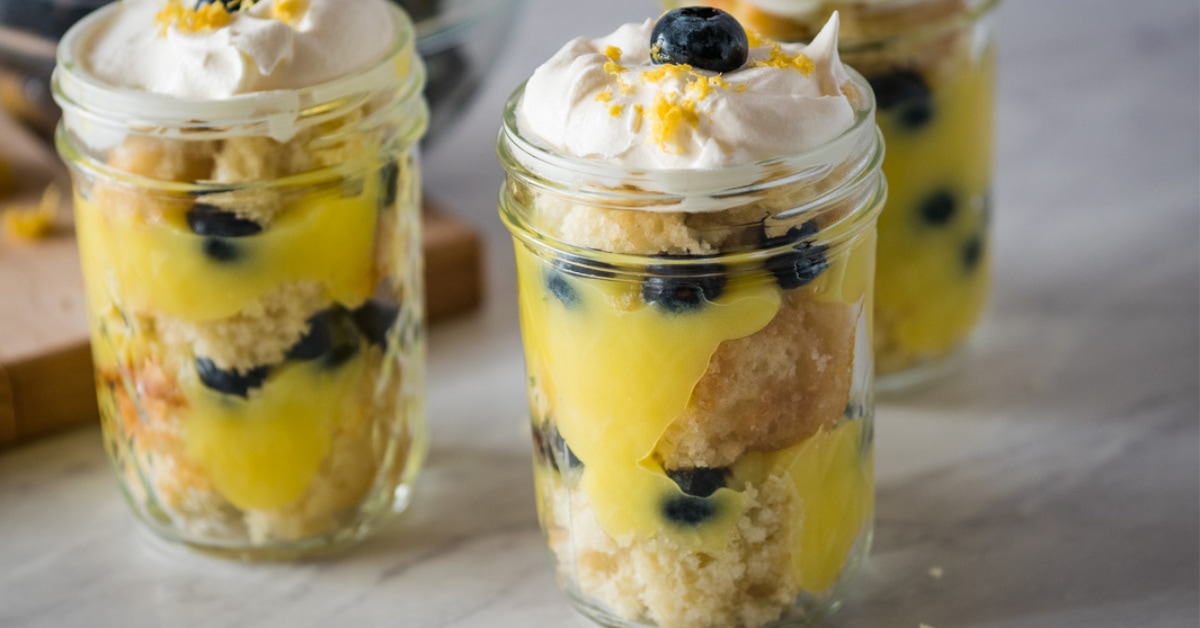 Three mason jars full of blueberry lemon trifle topped with whipped cream.