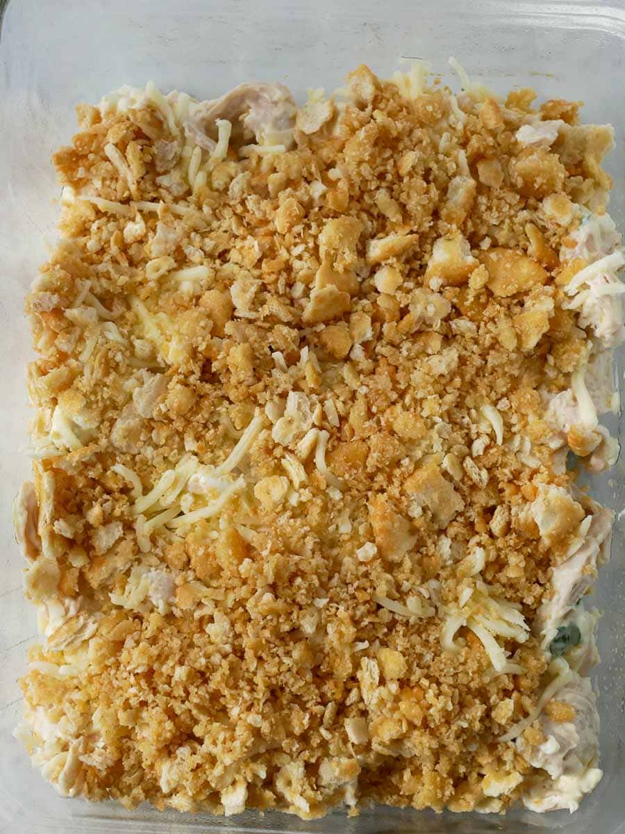 A casserole with a creamy filling topped with golden brown crumbled crackers and shredded cheese, viewed from above.