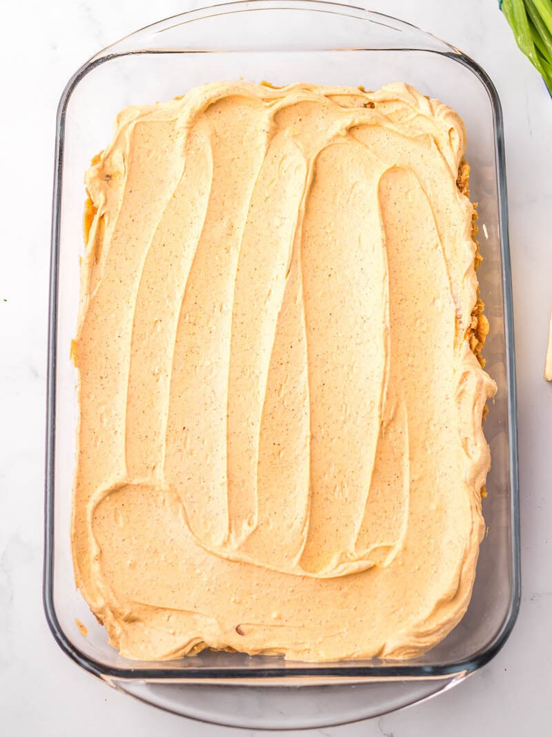 A rectangular glass dish filled cream cheese spread evenly on the surface.